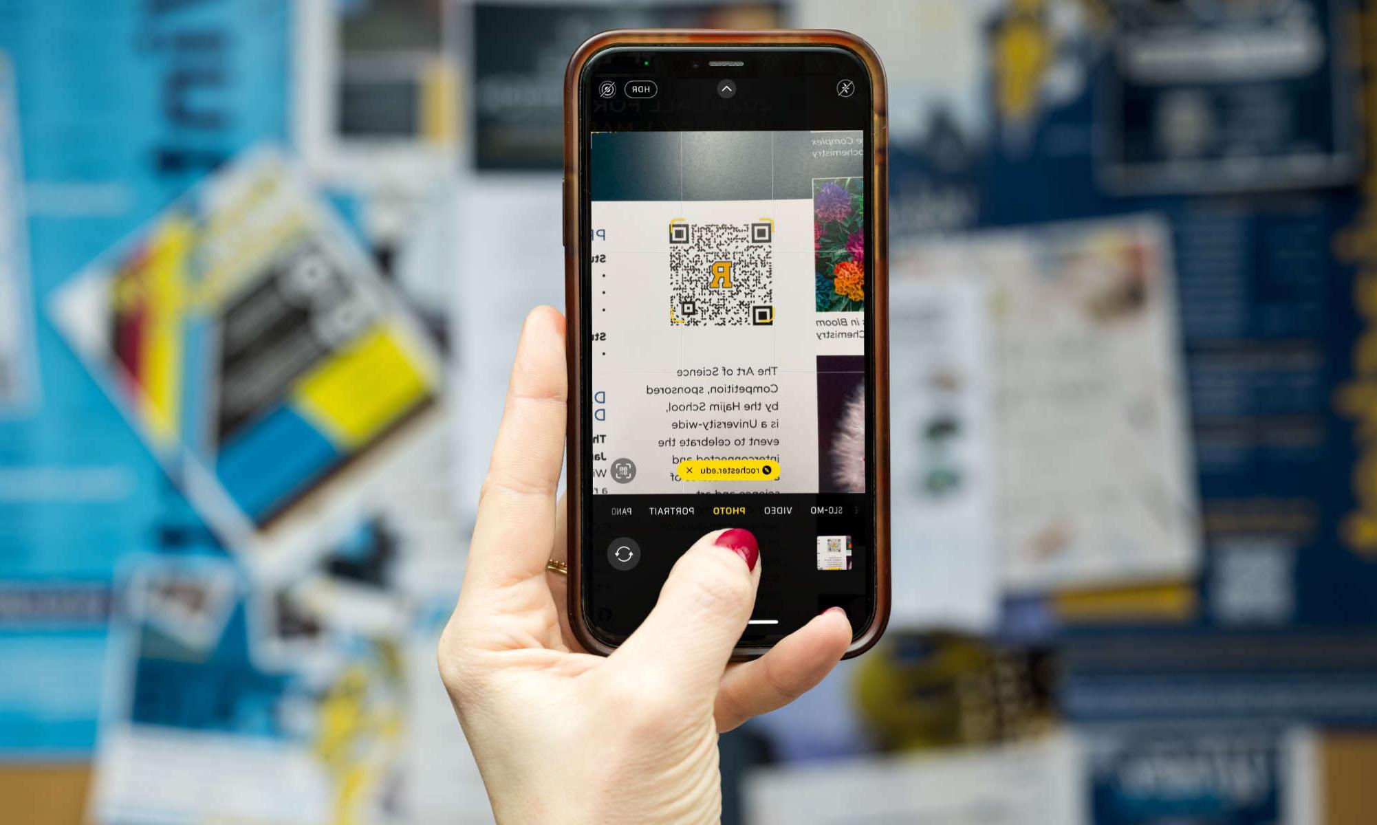 A hand holds up a phone and on the screen the new QR code technology to prevent quishing.